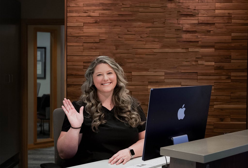 Woman team member waving at front desk.