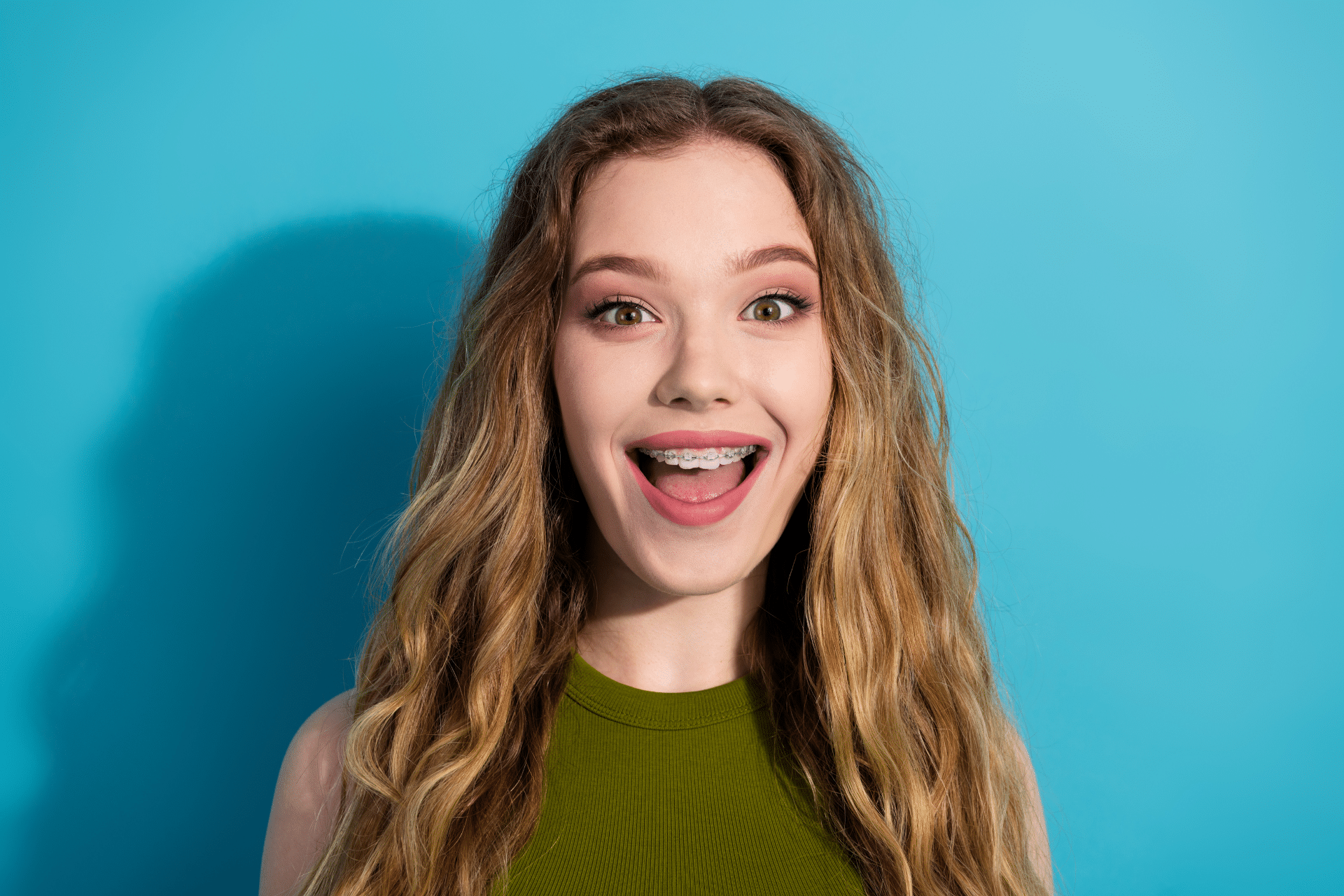Smiling young woman showing her braces against a blue background